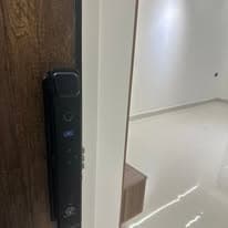 Close-up of an apartment entrance door with a digital lock and dark timber finish