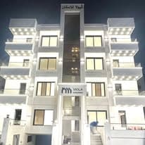 Viola Housing building lit at night, showing the balcony lighting and the illuminated company sign